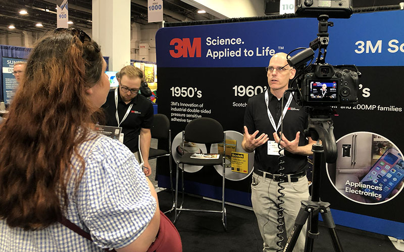 Behind the scenes shot of an interview being conducted with a 3M employee at a conference in Detroit. The interviewer is to the left and off camera.